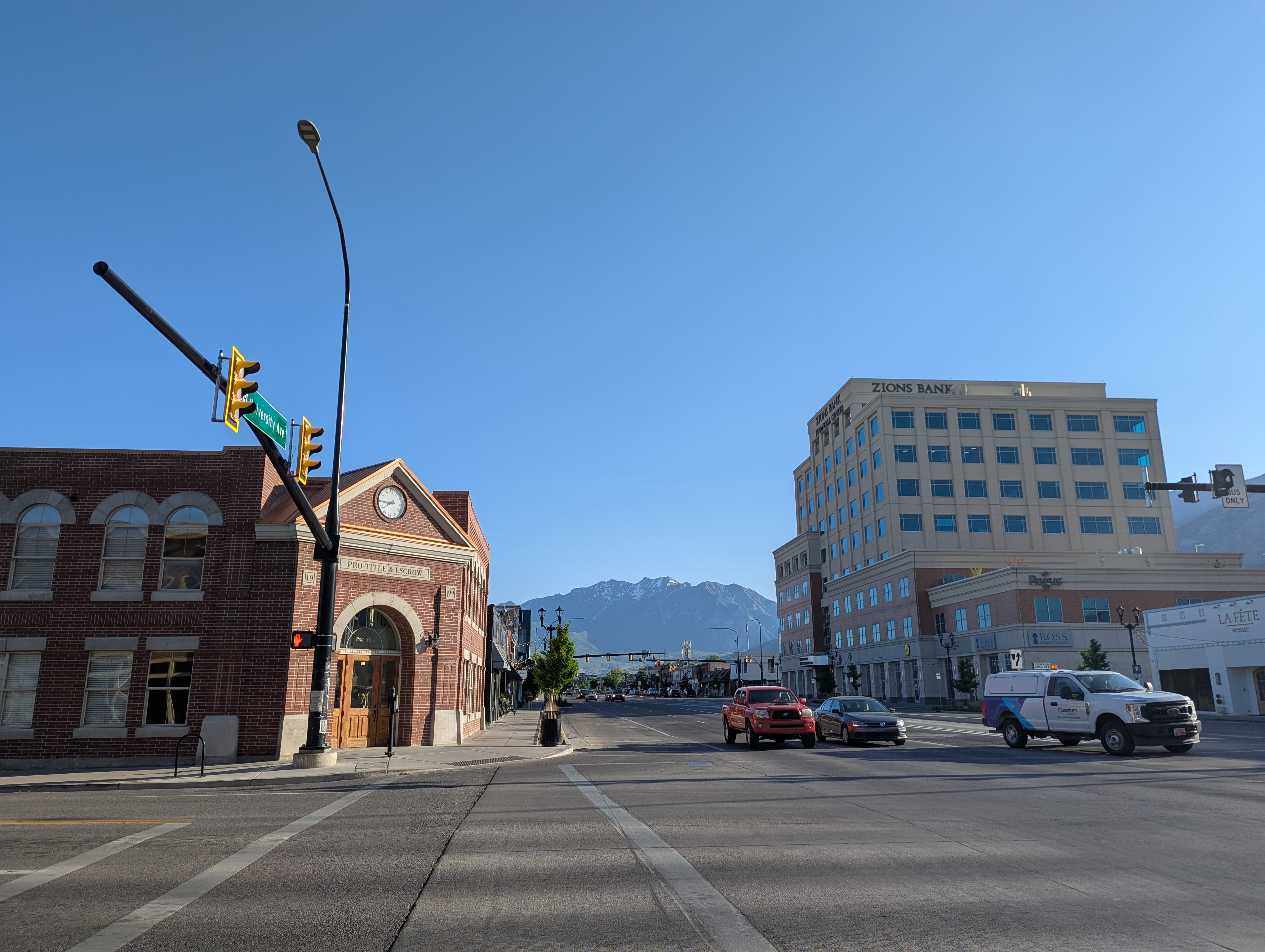 An intersection in a small city, with some Old West-style buildings and mountains in the background