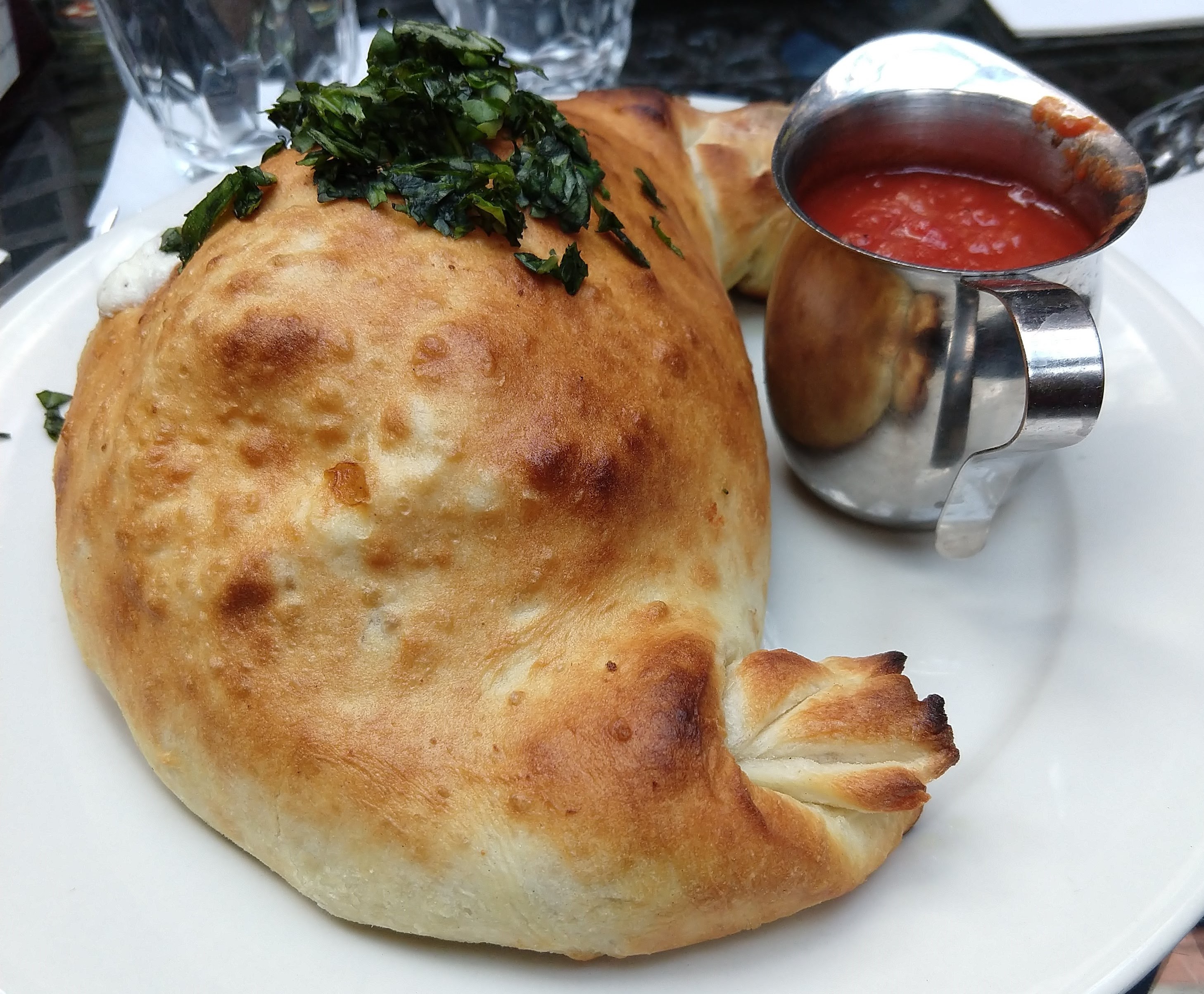 A calzone on a plate with a side of marinara sauce